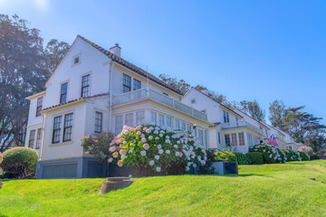 Wall Mural - Suburban houses on a sloped green lawn with flowering plants near the entrance in San Francisco, CA