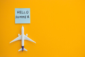 Wall Mural - Miniature toy airplane on color background and word hello summer. Trip by airplane.