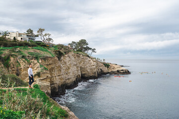 Young Japanese male in business clothes deep in thought while overlooking the Pacific ocean from a cliff edge