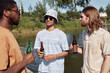© Seventyfour - Waist up portrait of three young men drinking beer outdoors and chatting in Summer setting