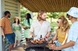 © Seventyfour - Waist up portrait of young people grilling meat outdoors with friends at barbeque party in Summer