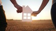 © maxximmm - paper house happy family. friendly family hands holding paper house the glare of the sun shine through the window a beautiful sunset. mortgage business construction concept. house dreams lifestyle