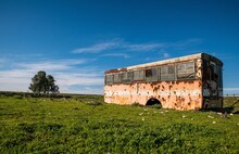 Beautiful View Of An Old Abandoned Bus In A Green Field Under Cloudy Sky