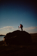 Man is taking photos of night sky with camera on tripod
