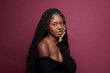© Jean Fotso/Stocksy - woman smiling wearing black dress and braids hair