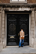 Girl In Fashionable Clothes Standing Next To Vintage Entrance Doors