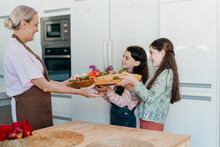 Grandma And Granddaughters With Coloredl Flowers In Kitchen