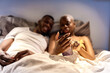 © Ezequiel Giménez/Stocksy - Black woman sharing social media data with men on bed