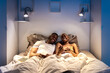 © Ezequiel Giménez/Stocksy - Black couple laughing at joke on bed at night