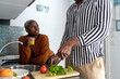 © Ezequiel Giménez/Stocksy - Crop man cutting vegetables in kitchen near girlfriend