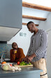 © Ezequiel Giménez/Stocksy - Joyful black couple chatting during lunch preparation