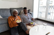 © Ezequiel Giménez/Stocksy - Young black couple eating salad sitting on floor