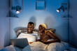 © Ezequiel Giménez/Stocksy - Black couple using laptop on bed at night