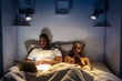 © Ezequiel Giménez/Stocksy - Black couple using devices on bed