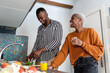 © Ezequiel Giménez/Stocksy - Joyful lady standing near boyfriend cooking in kitchen