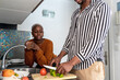 © Ezequiel Giménez/Stocksy - Crop black guy cutting veggies near girlfriend at home