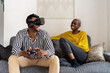 © Ezequiel Giménez/Stocksy - Happy black man playing VR videogame near girlfriend