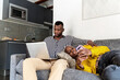 © Ezequiel Giménez/Stocksy - Black couple using gadgets on couch