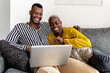 © Ezequiel Giménez/Stocksy - Merry black couple watching video on netbook