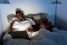 Black Man Using Laptop Near Sleeping Woman