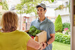 © ALTO IMAGES/Stocksy - Friendly male courier delivering groceries to client
