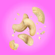 Leinwandbild Motiv Tasty cashew nuts flying on pink background