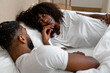 © Atolas/Stocksy - Young couple talking in bed