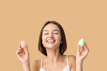 Sticker - Pretty young woman with makeup sponges on beige background