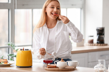 Mature woman eating tasty toasts in kitchen