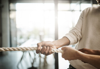 Poster - Man leading in teamwork tug of war challenge, employees collaborate working together pulling ropes in a competitive workplace. Business people having a rope to success in a modern office.