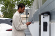 © Bisual Studio/Stocksy - Man using smartphone to pay at recharging station
