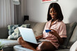 © David Prado/Stocksy - Smiling black woman with credit card and laptop
