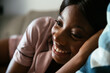 © David Prado/Stocksy - black woman lying on sofa happy