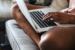 © David Prado/Stocksy - Crop woman using laptop on sofa