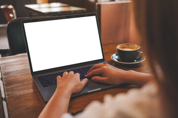 Wall Mural - mockup image of a woman using and typing on laptop computer with blank white desktop screen in cafe