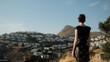 © Lucia Postike/Stocksy - A woman stands in front of a mountain and white houses