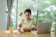 © Marc Tran/Stocksy - Businesswoman eating salad at desk
