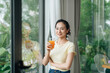 © Marc Tran/Stocksy - Smiling elegant businesswoman in bright office drinking orange juice