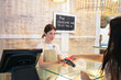 © Pedro Merino/Stocksy - Worker of a pastry shop charging a client with the dataphone