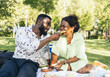 © Pedro Merino/Stocksy - Couple having picnic sitting on the grass