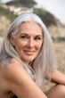 © Alba Vitta/Stocksy - Portrait of happy mature woman at the beach