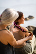 © Alba Vitta/Stocksy - Mother braiding hair to daughter at the beach