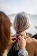 © Alba Vitta/Stocksy - Daughter braiding mother's hair in the beach