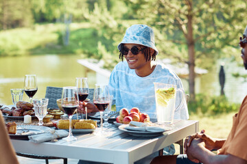 Wall Mural - Portrait of young black man smiling at table while enjoying dinner party with friends outdoors in Summer