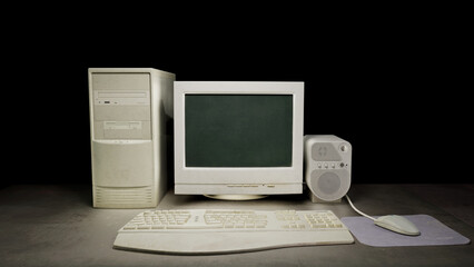 Old dirty computer with vintage monitor sitting on a dark table on a black background. With a vintage mouse, mousepad and keyboard. Next to a vintage old audio speaker. 3D rendering