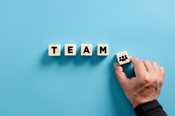 male hand puts the wooden cube with business team icon with the word team. business teamwork and syn