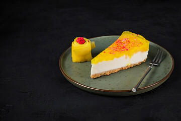 Canvas Print - A piece of mango cheesecake with mascarpone cream cheese filling, garnished with fresh mango, served on a plate with a dessert fork, dark background