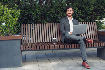 Sticker - Business man office worker working on laptop in urban park background and looking away