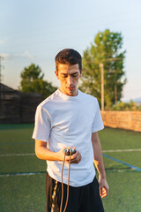 A young guy is jumping a rope outside in nature during the day