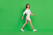 Full size profile photo of positive gorgeous girl have good mood walking isolated on green color background